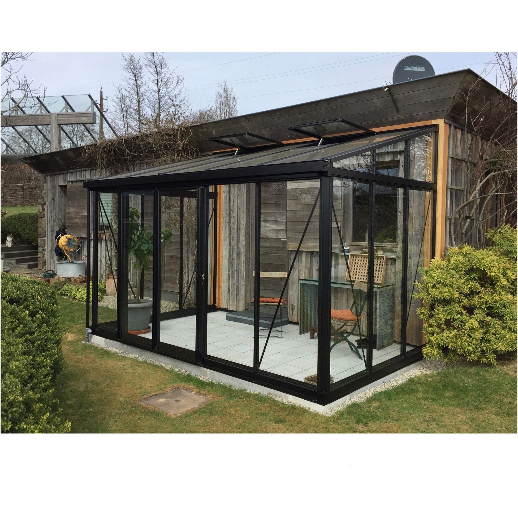 A relevant stock photo of lean to greenhouse in a typical setting.
